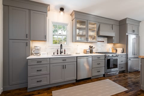 Contemporary kitchen featuring gray cabinets, stainless steel appliances, and a white countertop.