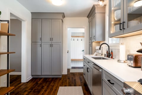 Modern kitchen with gray cabinets and an adjoining mudroom.