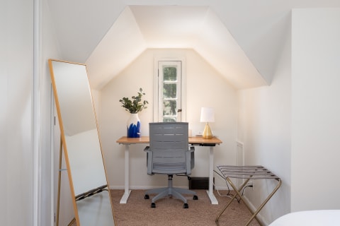 A cozy workspace with a wooden desk, gray office chair, and decorative elements including a lamp and a plant.
