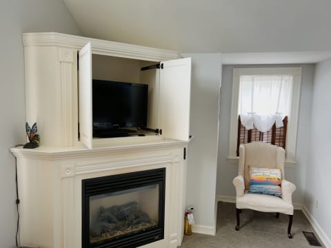 Cozy room featuring a fireplace, TV, and a comfortable armchair by a window.