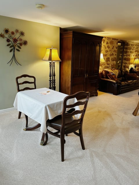 Cozy dining area featuring a small table with wooden chairs and a decorative lamp in warm lighting.