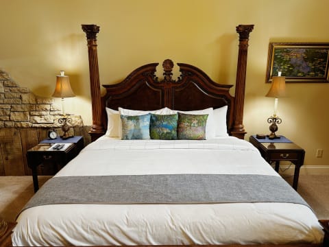Elegant four-poster bed with decorative pillows in a well-styled bedroom featuring warm lighting and rustic decor.