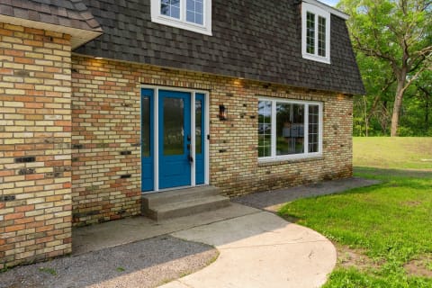 Exterior view of a house featuring blue double doors and a brick wall.