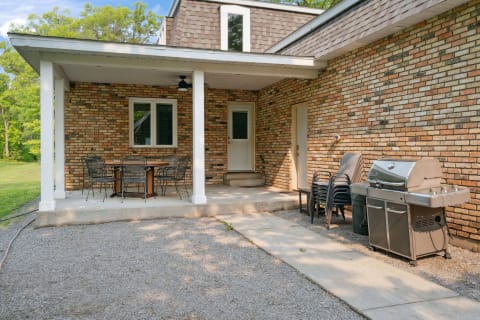 Outdoor patio with a table and grill next to a brick house.