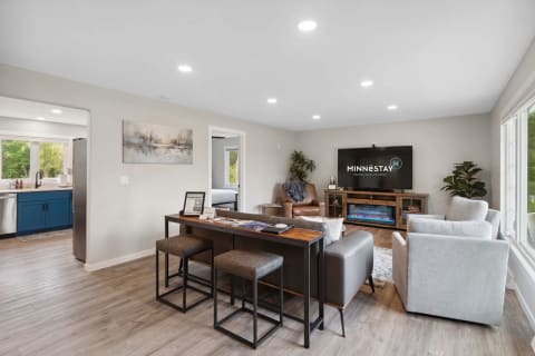 Modern living space featuring light grey armchair and blue kitchen cabinets.
