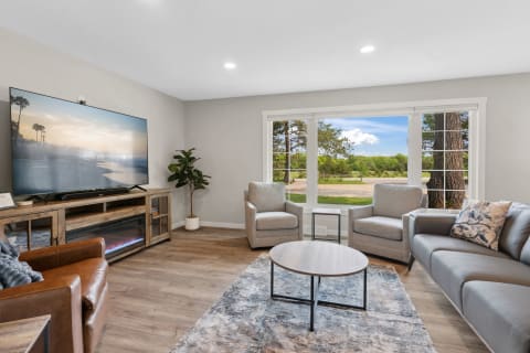Modern living room with a TV, comfortable seating, and a view of the outdoors.