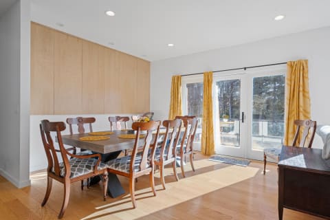 A spacious dining room featuring a wooden table with chairs and large sliding glass doors leading outside.