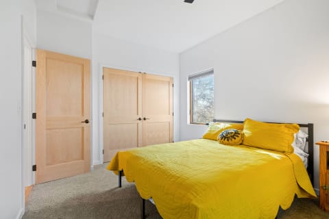 A cozy bedroom with a yellow bed and bright natural light coming through the window.