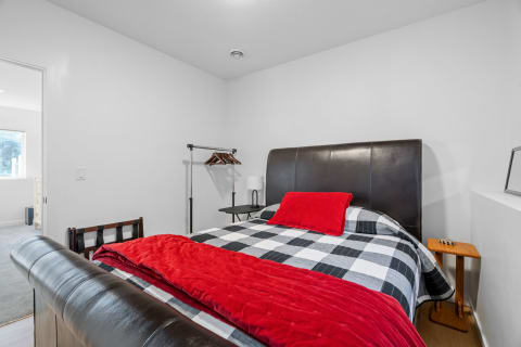 Modern bedroom featuring a large leather headboard, black and white checkered bedding, and red accents.