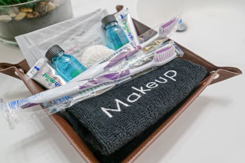 A basket containing a makeup towel, toothbrushes, toothpaste, and personal care products.
