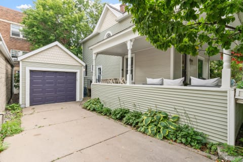 House exterior with a porch and garage under a blue sky.