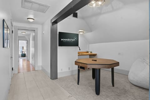 A bright game room on the third floor featuring a wall-mounted TV and a modern game table.