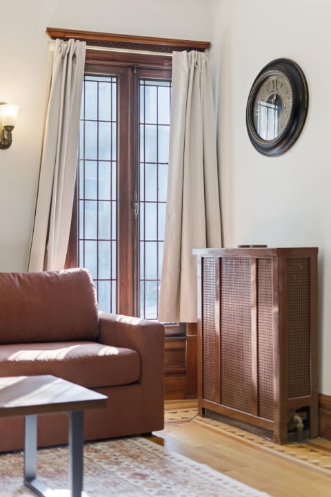 Cozy sitting area featuring a brown sofa, French doors, and vintage radiator in natural light.