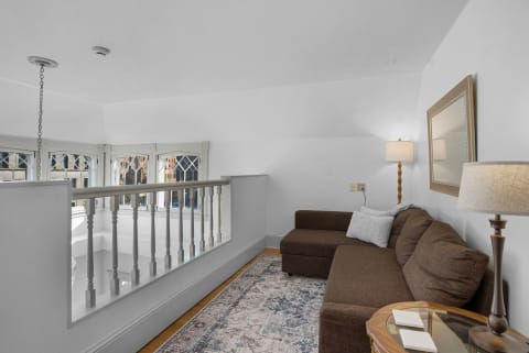 A cozy upstairs living nook with brown sectional couch, soft lighting, and elegant windows.