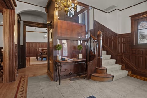 A grand foyer featuring rich wood paneling, a sweeping staircase, and an elegant chandelier.