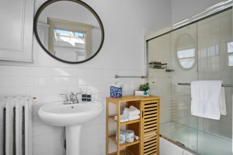 Modern bathroom with pedestal sink, mirror, and glass shower.