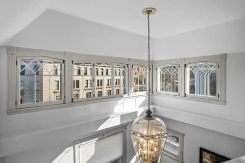 Bright room with historic windows and a pendant light, showcasing architectural elegance.