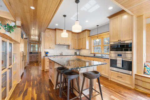 Modern kitchen with wood cabinets, granite countertops, and island seating.