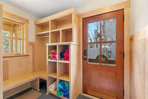 A cozy entryway featuring cubbies filled with colorful towels and a wooden door with a glass window.