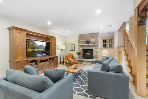 Cozy living room with gray sofas, a stone fireplace, and a wooden entertainment unit.