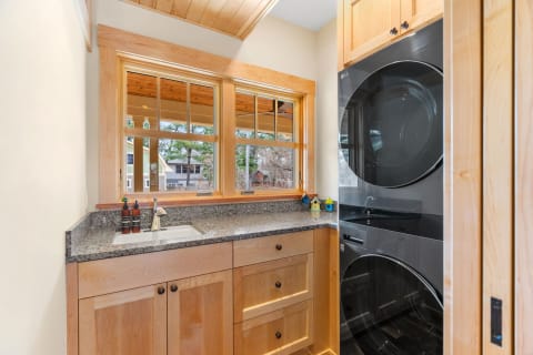 Modern laundry room featuring wood cabinets and black washer and dryer.