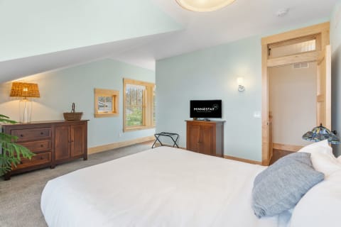 Cozy bedroom featuring a bed, wood dresser, and large windows.
