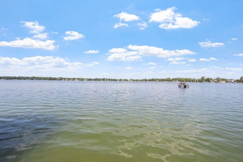 A calm lake with a small boat and fluffy clouds overhead.