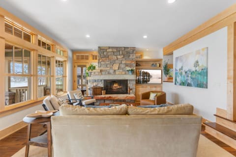 Cozy living room with a stone fireplace and large windows.