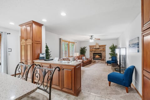 Living room with leather sofa, stone fireplace, and blue accent chairs.
