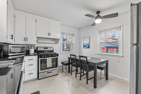 Modern kitchen with white cabinets, black countertops, and a dining area.