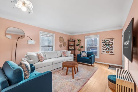 Cozy living room with peach walls, light sofa, teal armchair, and butterfly wall art.