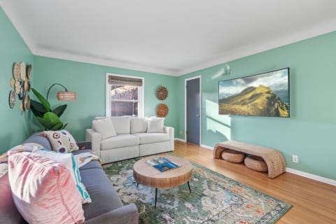 A living room with mint green walls, grey and white sofas, and a wooden coffee table.