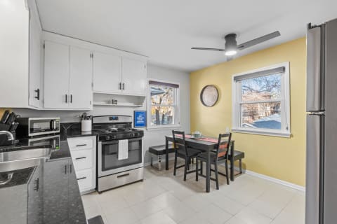 Modern kitchen with white cabinets, black countertops, and a small dining area.