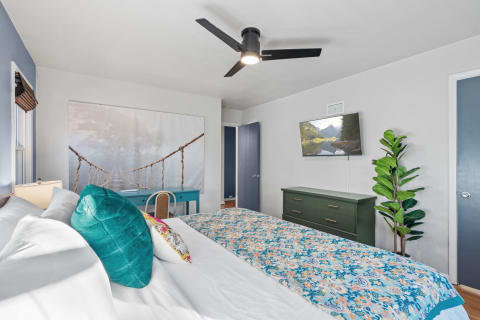 Cozy bedroom with a bed, colorful decor, and a nature mural.