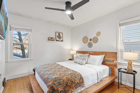 Inviting bedroom with a wooden bed, colorful blanket, and decorative wall hangings.