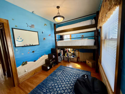A children's bedroom with a bunk bed, blue walls decorated with ocean life, and a whiteboard.