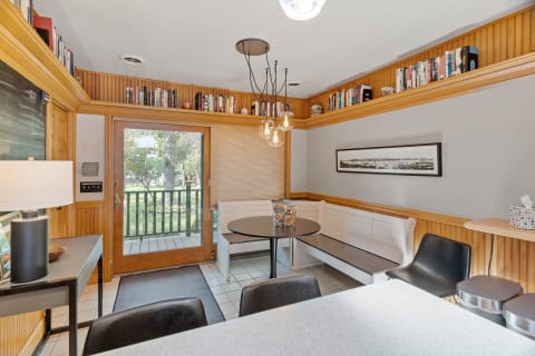 A bright dining nook featuring a round table, built-in seating, and shelves of books.