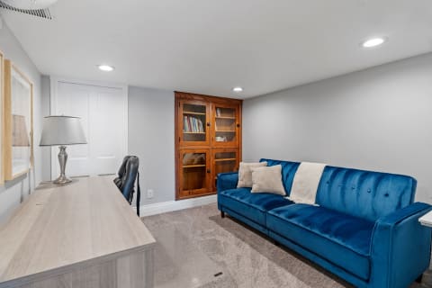 Cozy living area with a blue sofa, wooden desk, and bookshelf in a modern design.