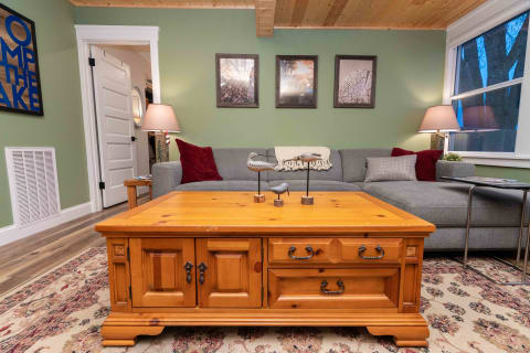 A living room with a wooden coffee table, gray sectional sofa, and decorative bird figurines.