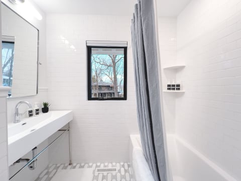 Contemporary bathroom with white tiles, a stylish sink, and a window view.