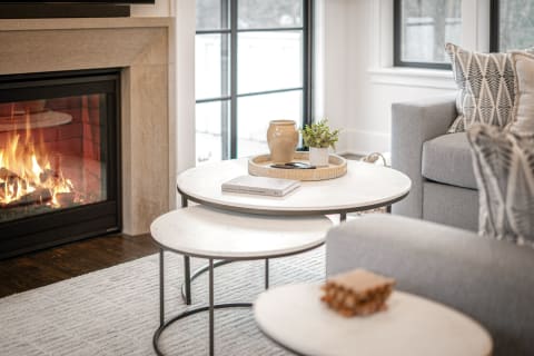 Living room with fireplace, gray sofa, and round coffee tables.