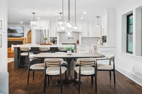 Modern kitchen and dining area featuring white cabinetry, pendant lights, and a stylish dining table.