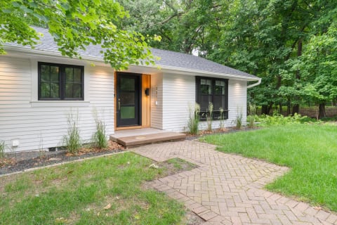 Exterior view of a modern house with a wood accent entrance surrounded by greenery.