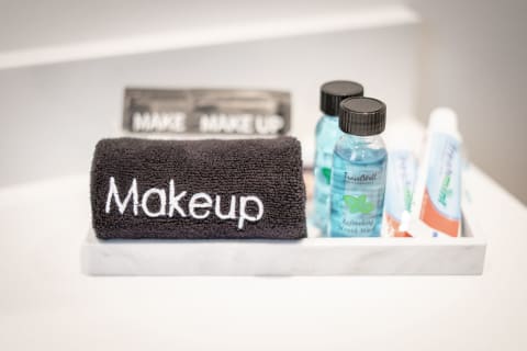 A black towel labeled 'Makeup', surrounded by mouthwash bottles and toothpaste on a marble tray.