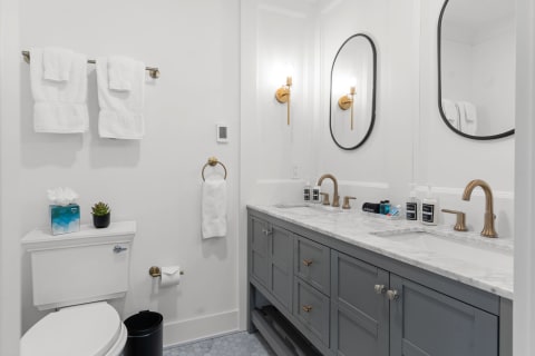 Elegant bathroom featuring a grey vanity, marble countertop, and stylish mirrors.