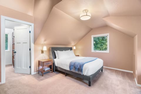 Cozy bedroom with a bed, reading lights, and natural light from a window.