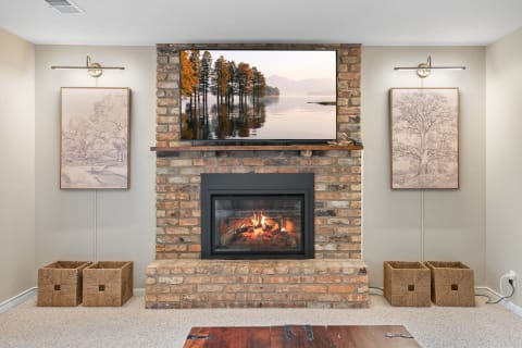 Living room featuring a brick fireplace with a TV above it and framed artwork on the walls.