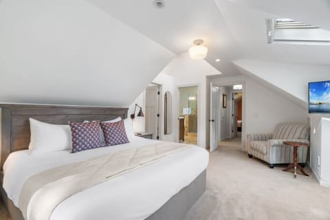 Cozy loft bedroom featuring a large bed, decorative pillows, and an armchair.
