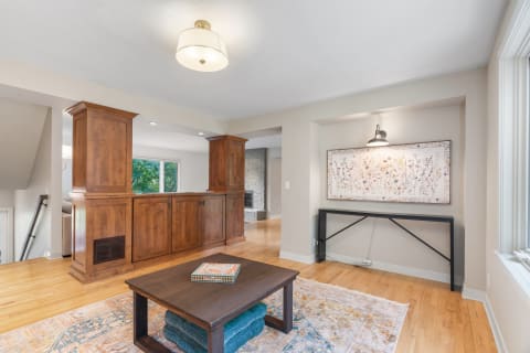 Interior view of a cozy living room with wooden cabinetry and floral art.