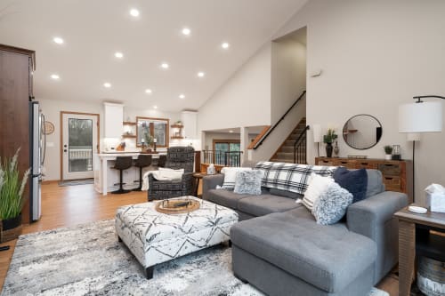 Sink into plush gray sectionals in your open-concept haven, where modern comfort meets rustic charm with warm wood accents throughout.